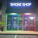 A smoke shop illuminated by vibrant neon lights, set against a dark background, creating a striking visual contrast.